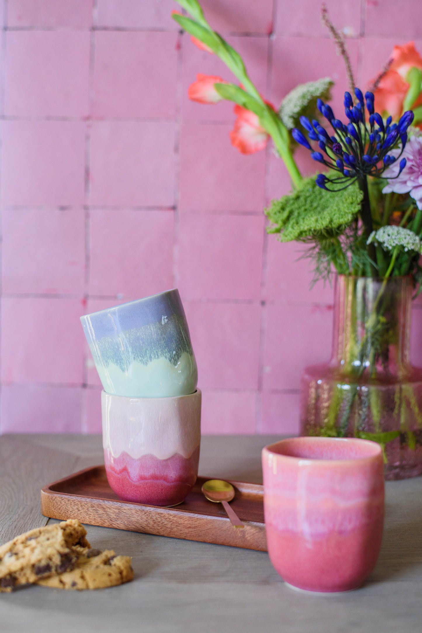 sfeerfoto van 3 handgemaakte koffiekopjes op een tafel met serveerplankje en lepeltje