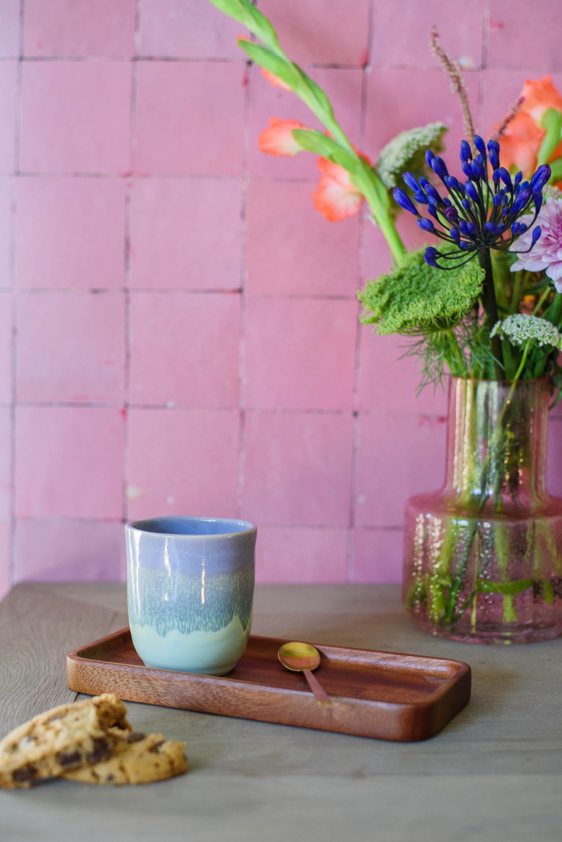 sfeerfoto met een handgemaakt koffiekopje voor een roze muur in de kleur paars groen met kleurverloop