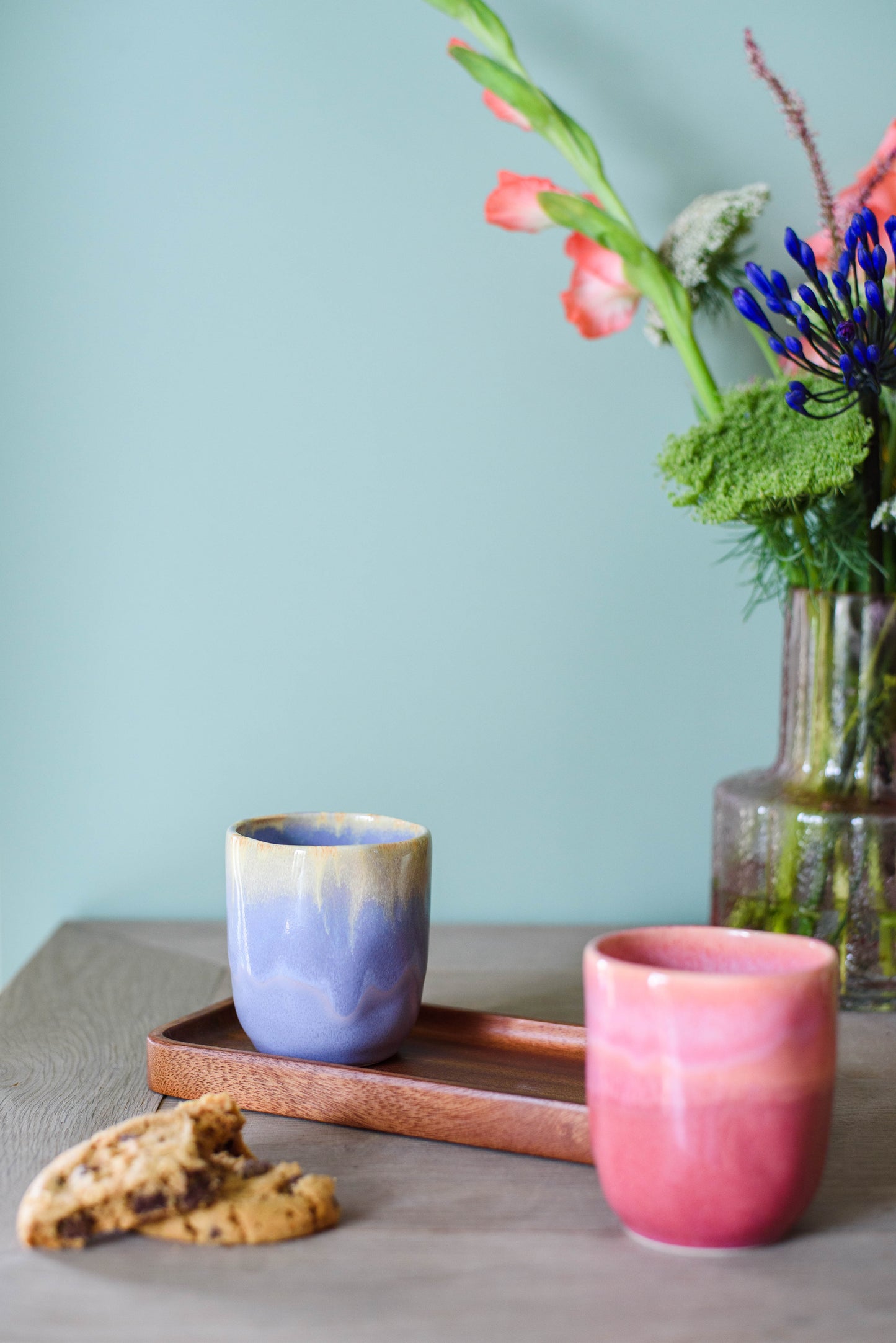 sfeerfoto met 2 koffiekopjes zonder oor op tafel, in de kleuren roze en paars/geel met kleurverloop