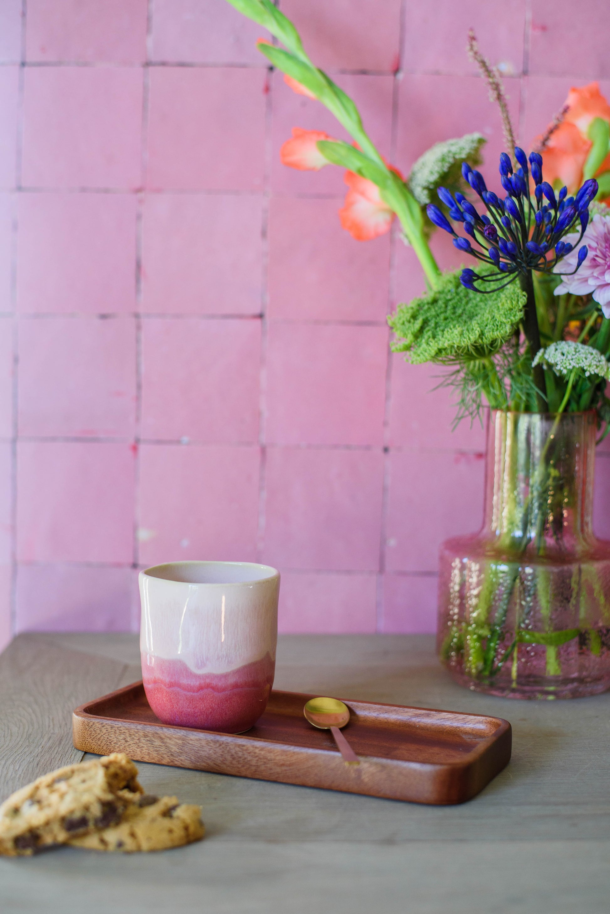 sfeerfoto voor een roze tegelmuur en een tafel met koffiekopje zonder oor in roze
