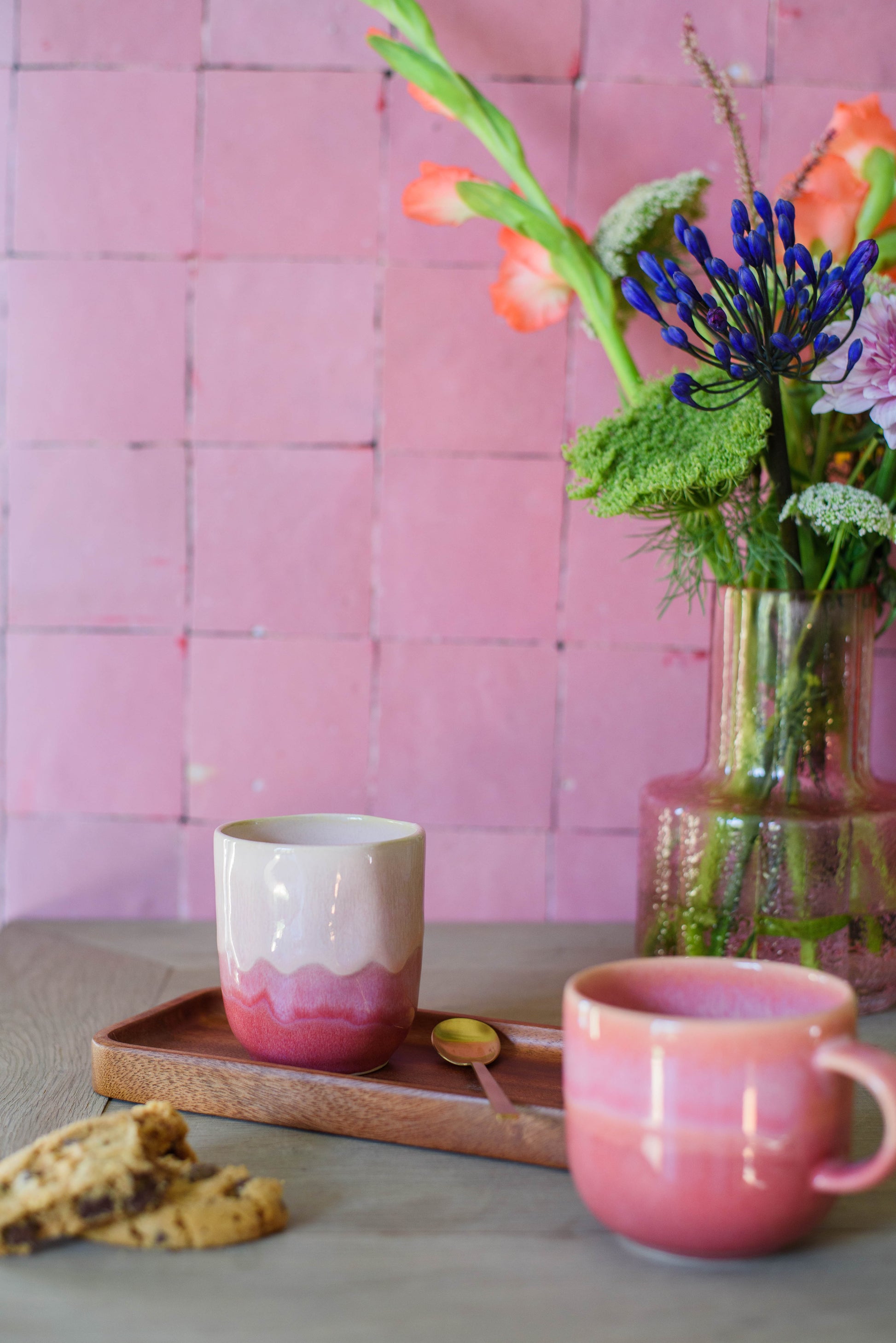 sfeerfoto voor een roze tegelmuur van 2 handgemaakte keramieken mokken in de kleur roze