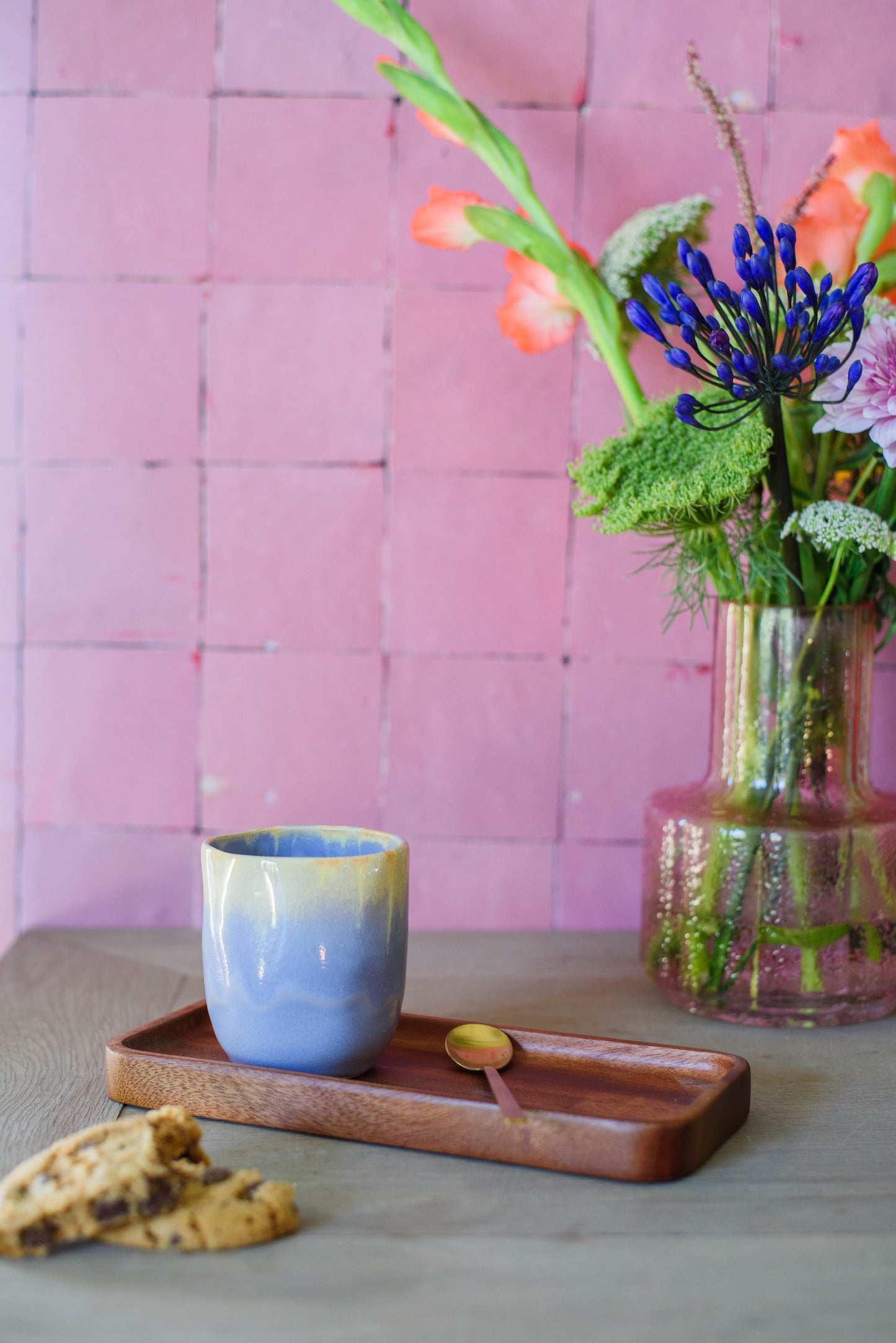 sfeerfoto van uniek handbeschilderd koffiekopje zonder oor in de kleur paars en geel, voor een roze muur